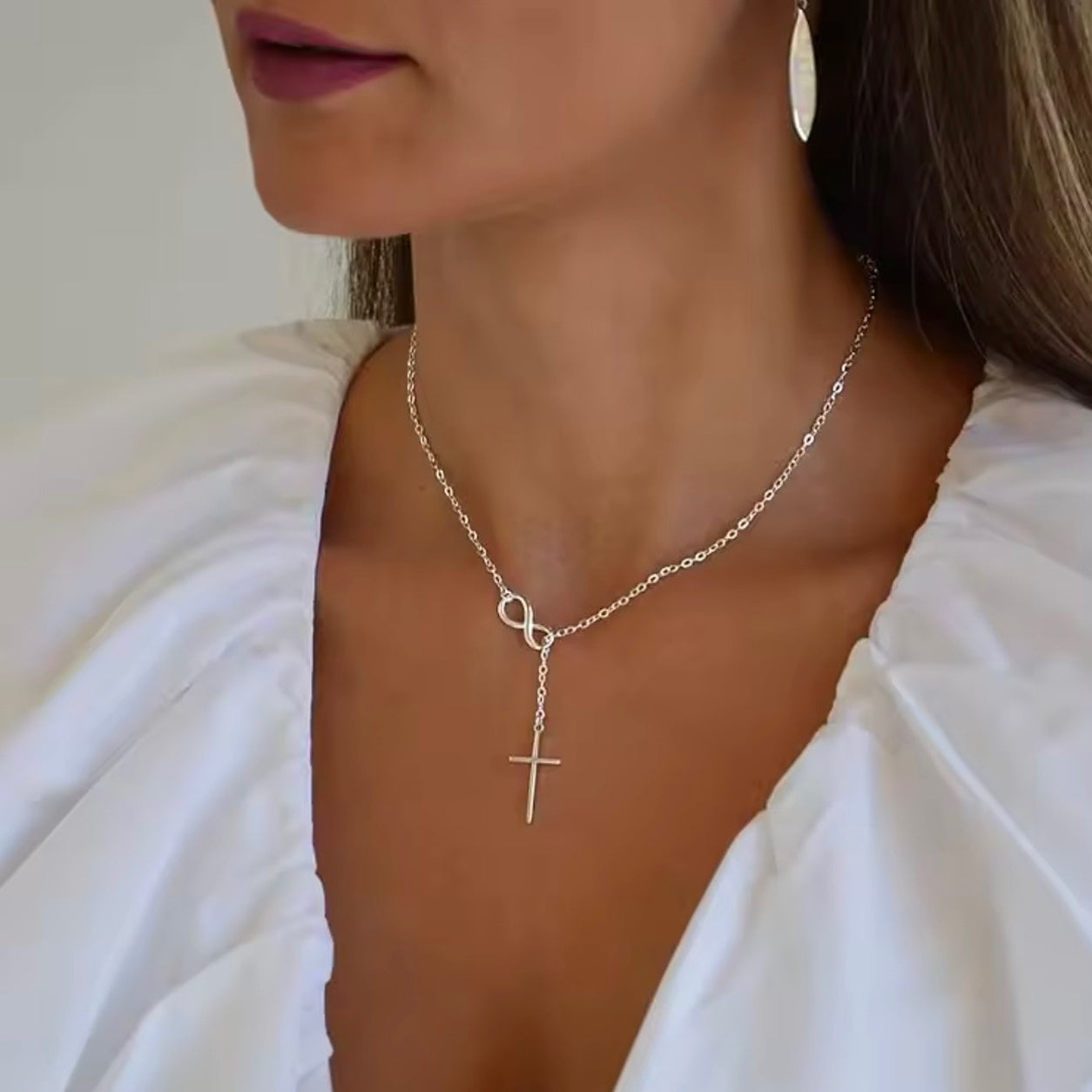 Woman wearing the sterling silver Infinity Cross Necklace with an elegant infinity symbol and dangling cross pendant.