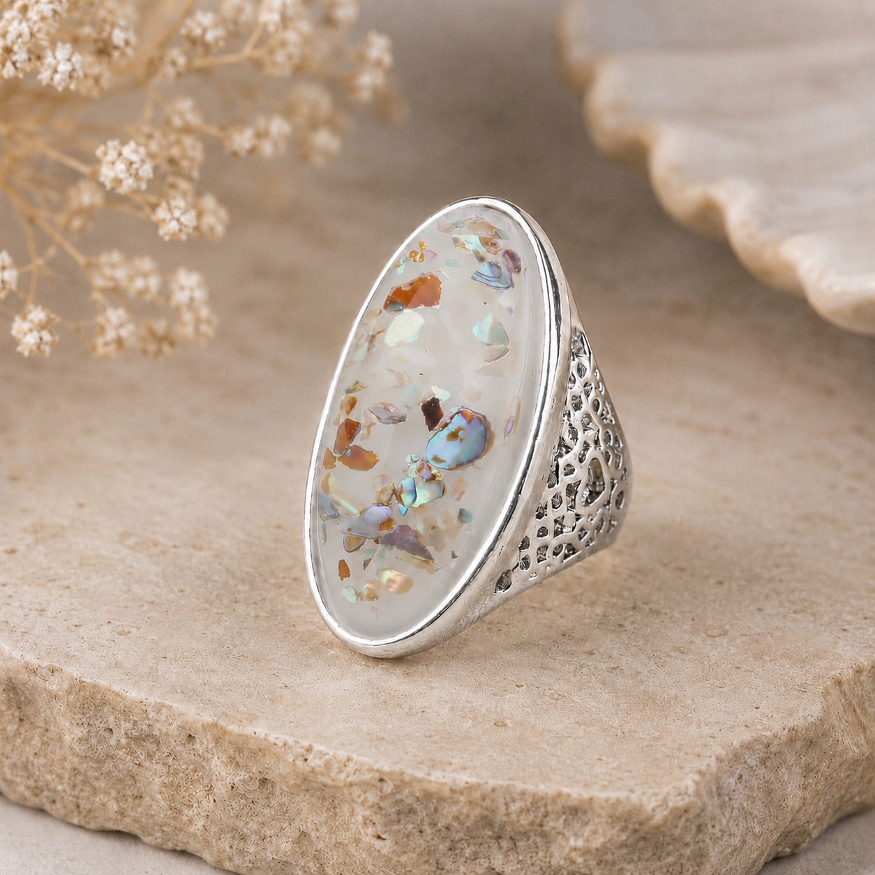Abalone Shell Statement Ring with iridescent shell in a polished silver setting on a natural stone display.