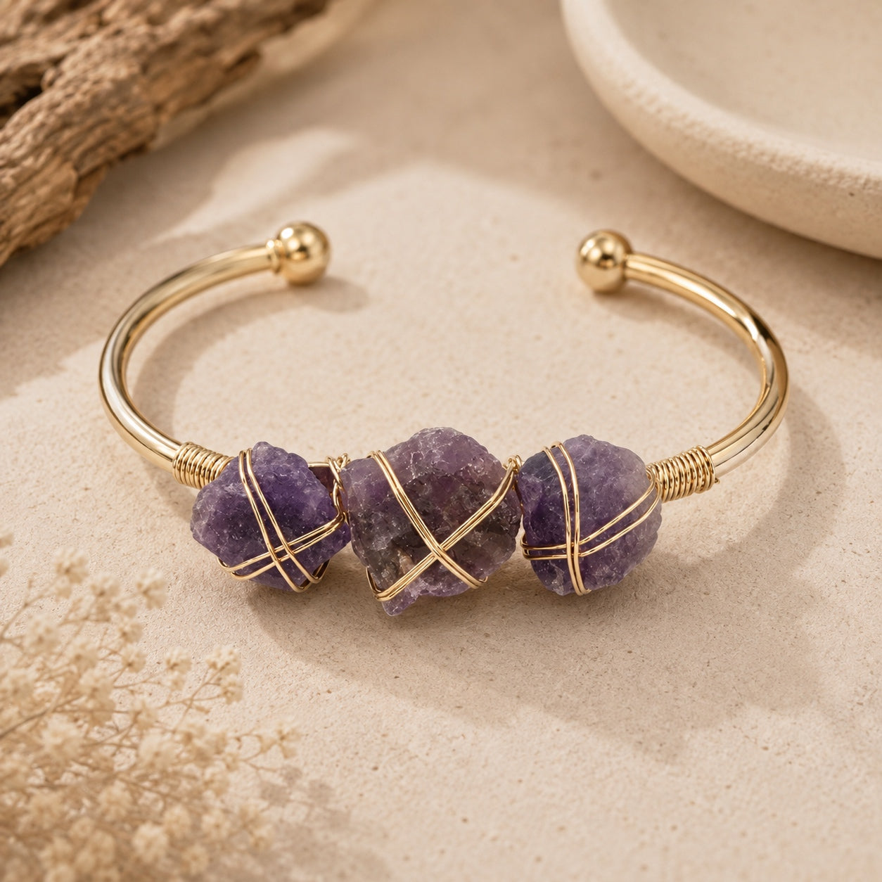 Amethyst stone cuff bracelet with three raw purple crystals wrapped in gold-tone wire.