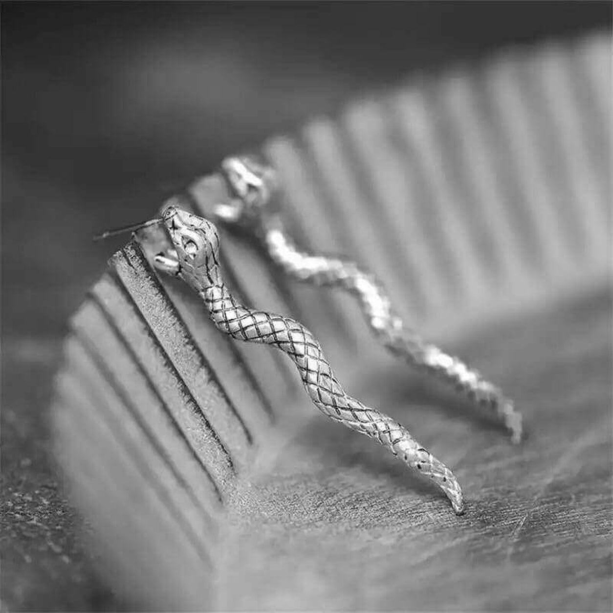 Ancient Silver Snake Earrings resting on a jewelry display, showcasing intricate snake design and vintage silver detailing.