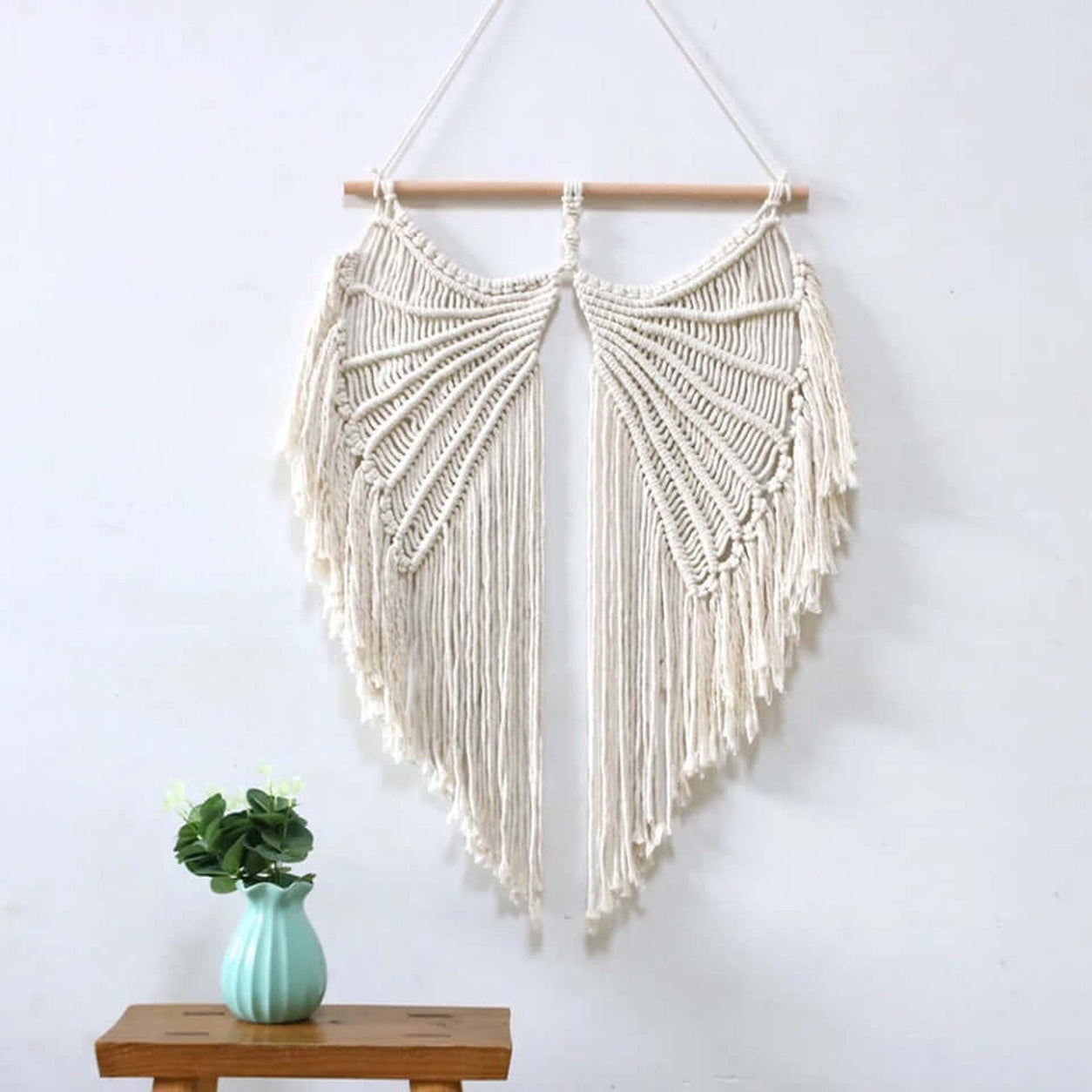Angel Wings Macrame Wall Hanging displayed on a wall above a wooden table with a decorative vase in a boho home.
