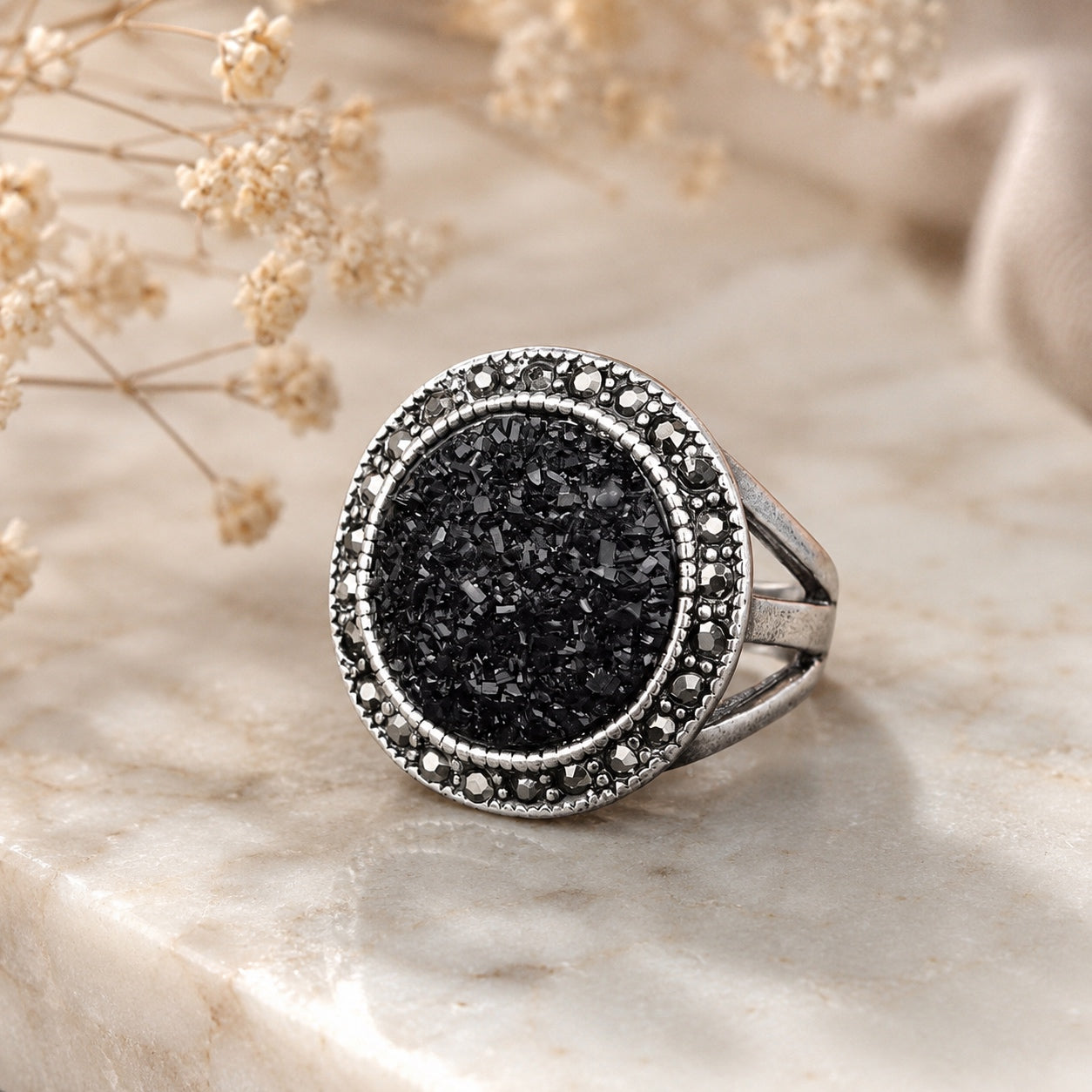 Black Druzy Statement Ring with sparkling black druzy stone and vintage silver setting displayed on a marble surface.