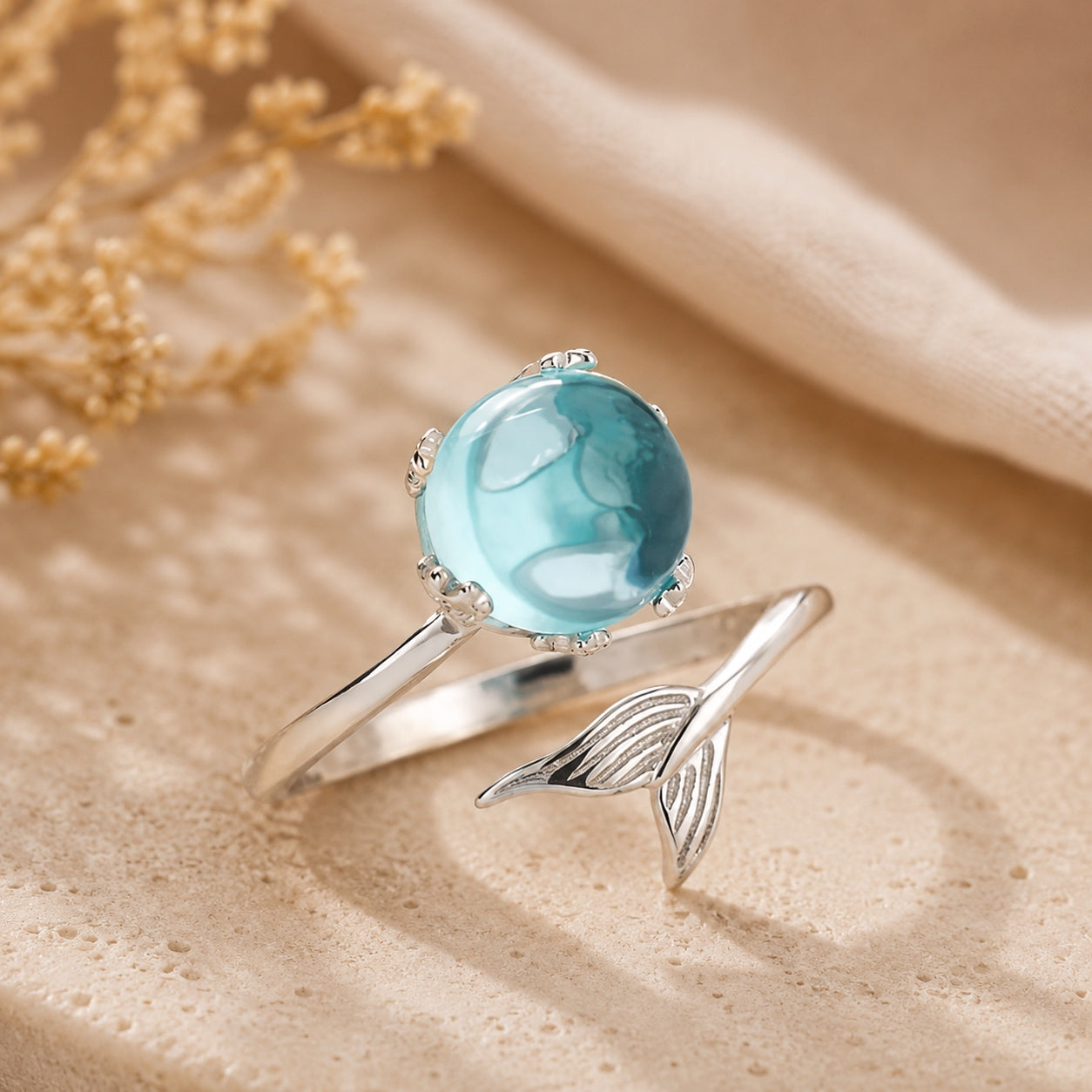 Angled view of the Blue Crystal Mermaid Ring with a luminous blue crystal and elegant silver mermaid tail design.