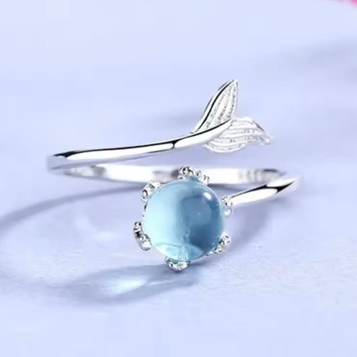 Front view of the Blue Crystal Mermaid Ring with a glowing blue crystal in an adjustable silver mermaid tail ring.