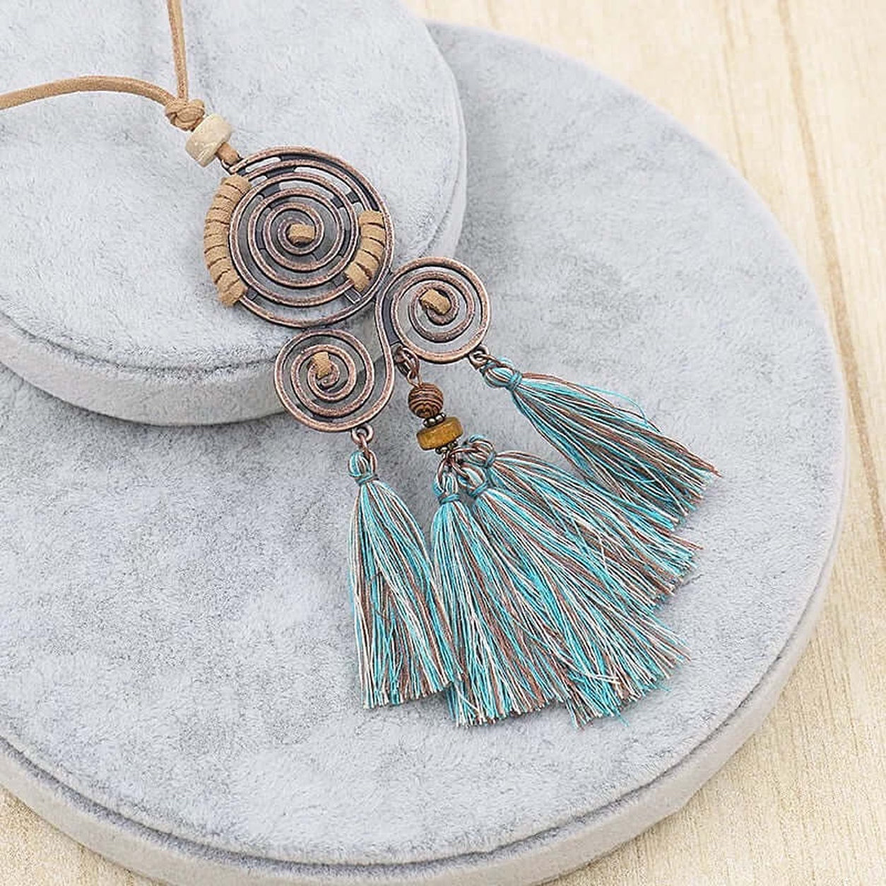 Close-up of the Boho Spiral Tassel Necklace featuring copper-tone spiral pendants, turquoise tassels, and a faux suede cord.