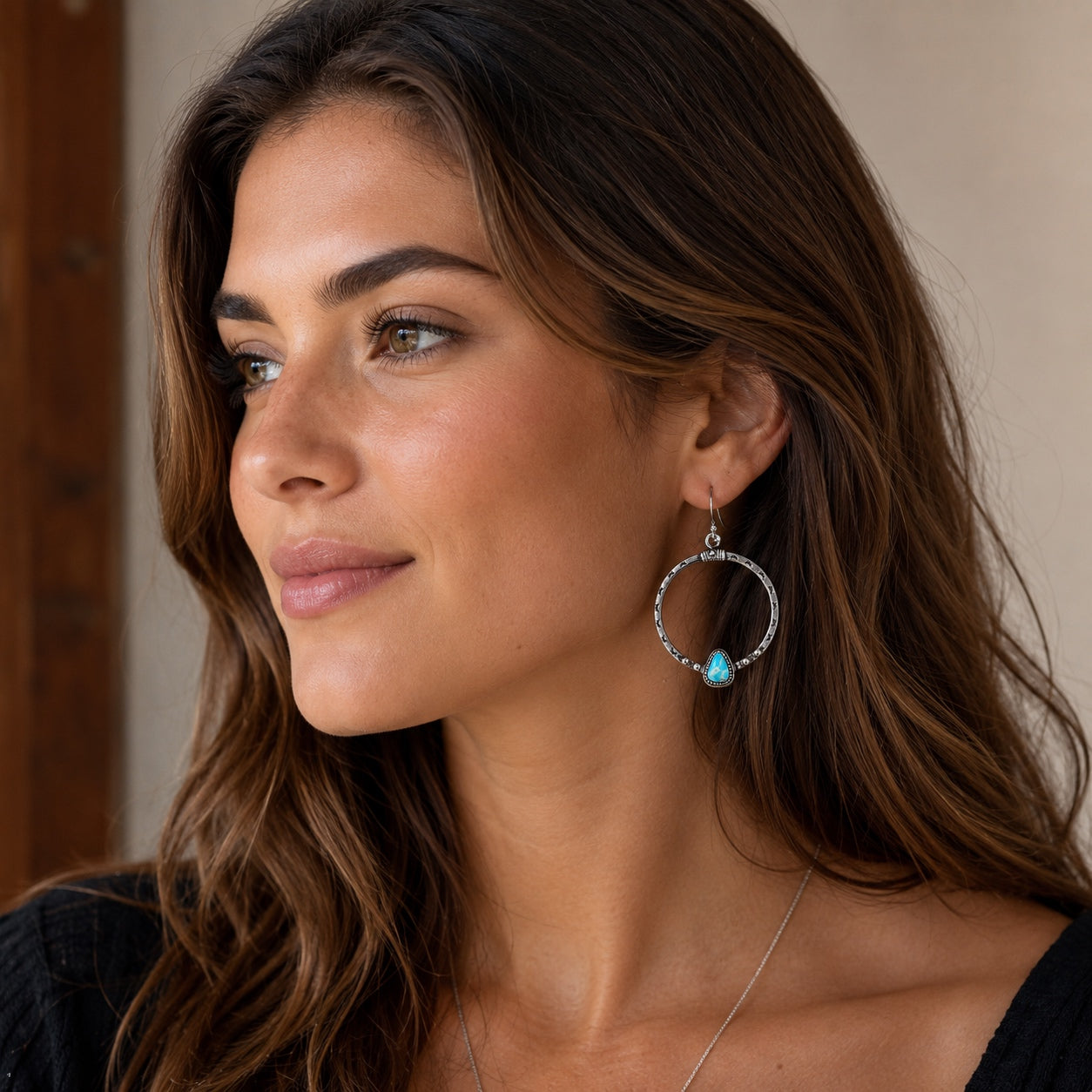 Model wearing Canyonlands Hoop Earrings featuring engraved silver hoops with turquoise teardrop stones.