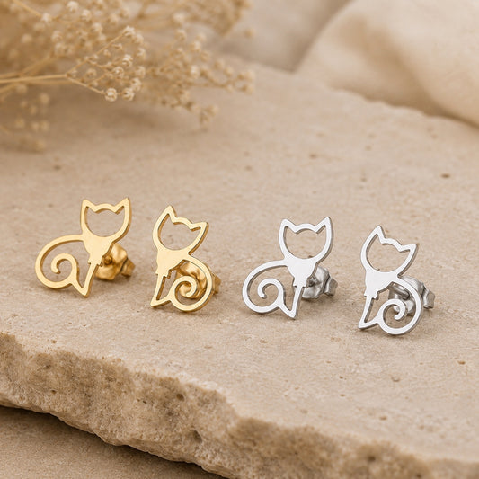 Gold and silver cat stud earrings with minimalist cat silhouette design displayed on a natural stone background.