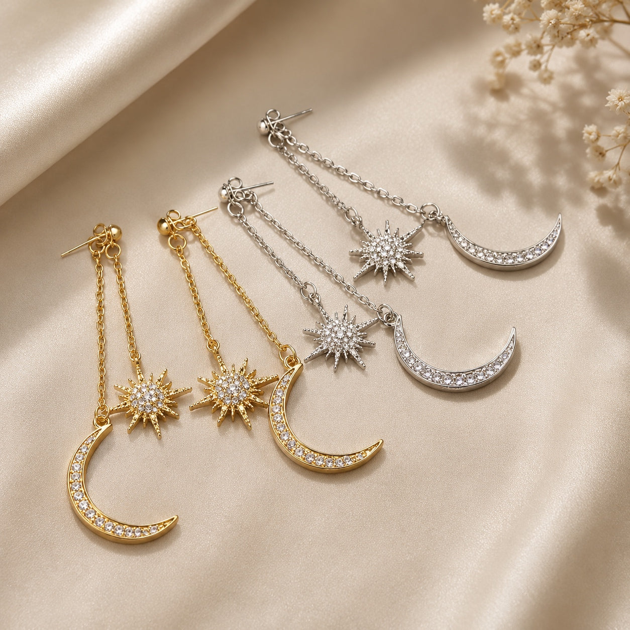 Celestial Dangle Earrings in gold and silver finishes with sparkling moon and star charms displayed on champagne satin.