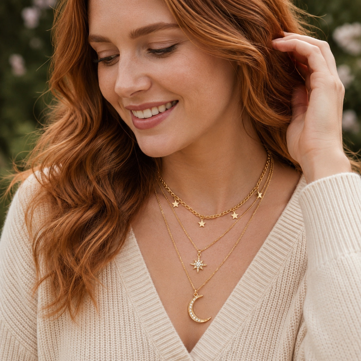 Gold celestial layered necklace with star charms, starburst pendant and crescent moon worn on a woman.