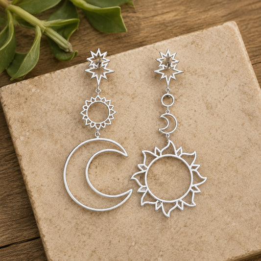 Silver Celestial Wanderer Earrings featuring celestial sun and moon dangle earrings displayed on natural stone.