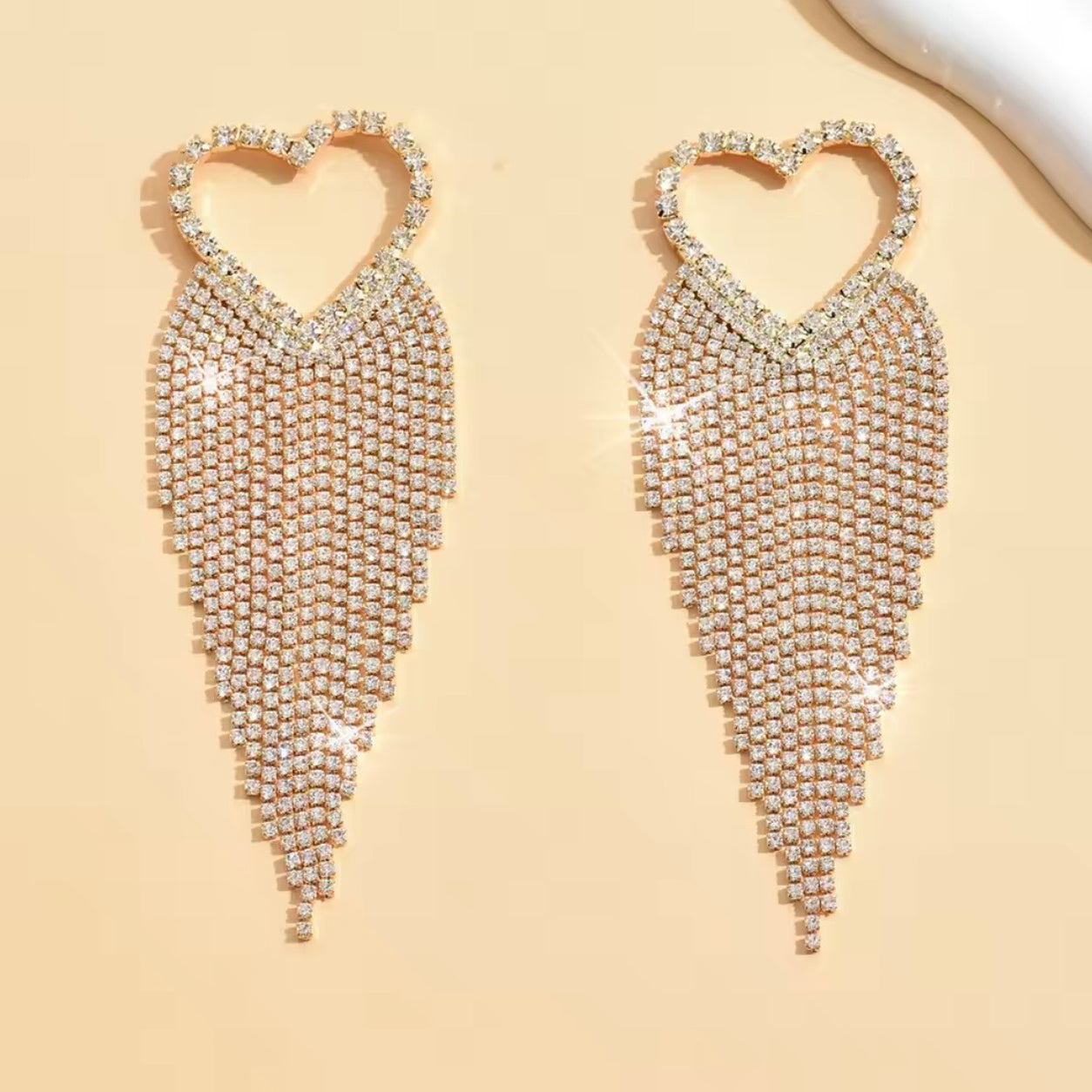 Crystal Heart Dangle Earrings in gold featuring shimmering rhinestone hearts and elegant cascading crystal tassels.