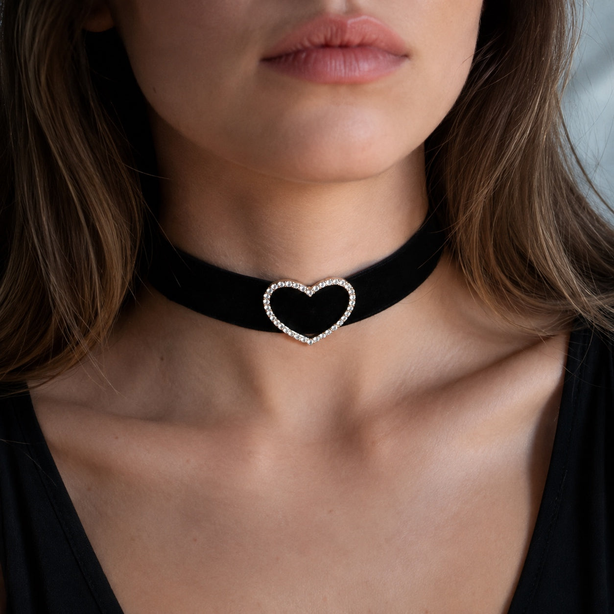 Close-up of a woman wearing the Crystal Heart Velvet Choker with a sparkling heart on a black velvet band.