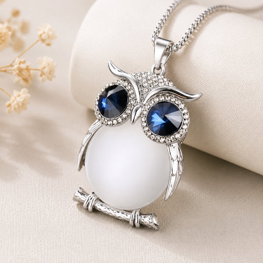 Close-up of the Crystal Owl Pendant Necklace featuring sparkling blue crystal eyes, a silver owl design, and a luminous white stone pendant.