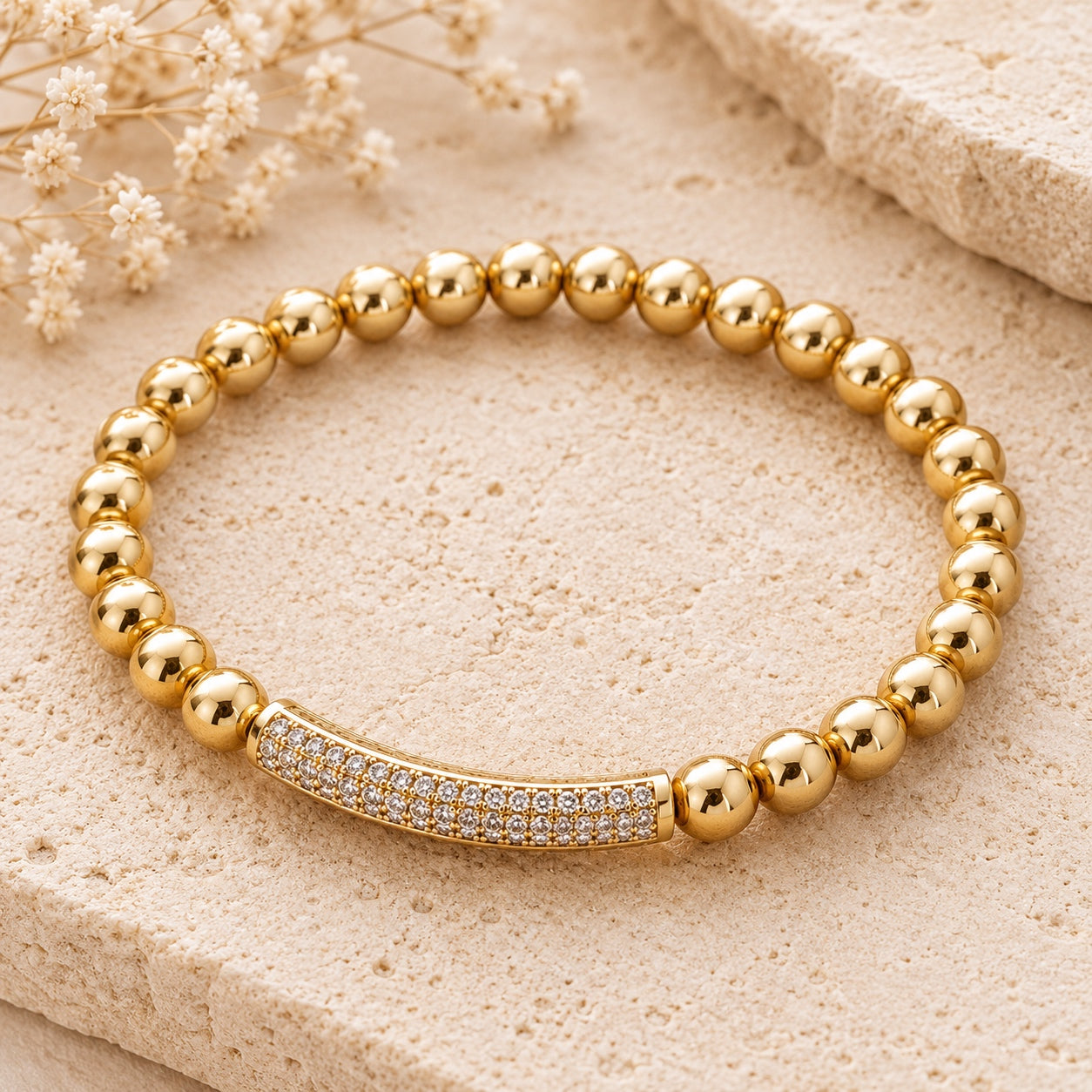 Close-up of a single gold beaded bracelet with a curved crystal pavé bar from the Crystal & Stone Bracelet Stack, displayed on a textured stone background.