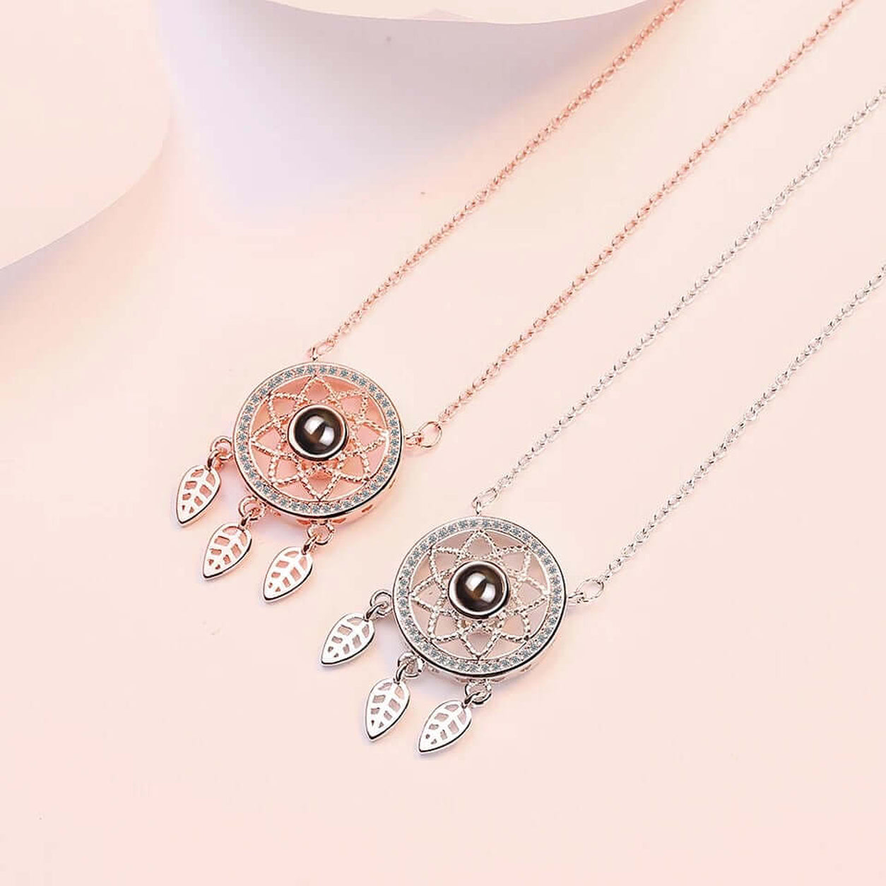 Silver and rose gold Dreamcatcher Necklace displayed together featuring an intricate dreamcatcher pendant and dangling leaves.