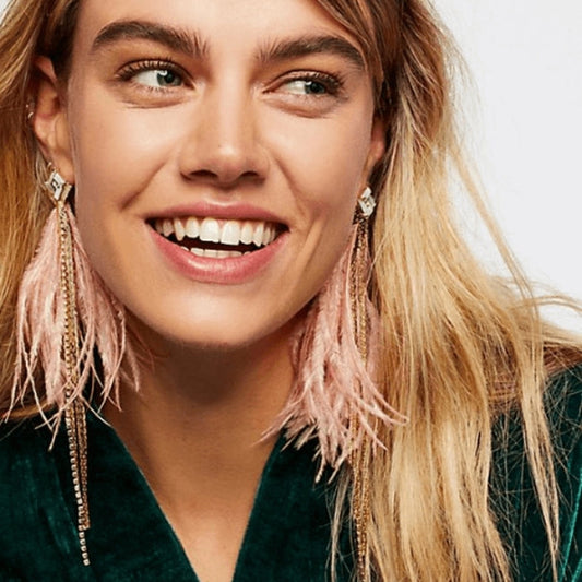 Model wearing Elegant Feather Earrings in pink with sparkling crystal studs, soft feathers, and delicate chain accents.
