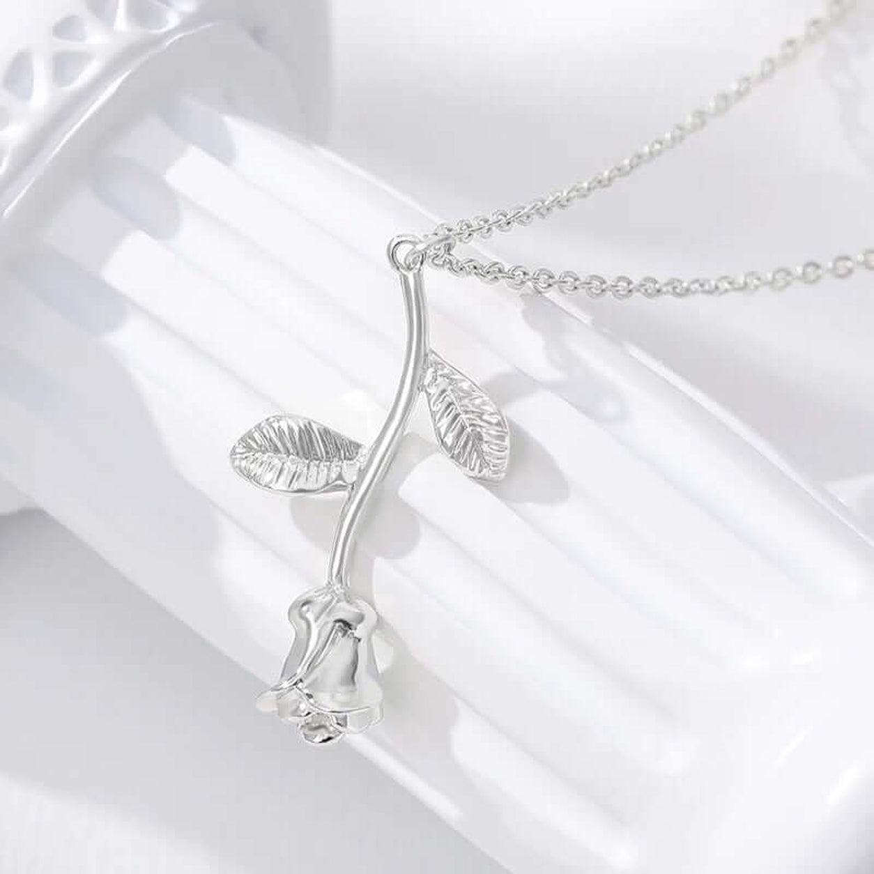 Elegant Rose Pendant Necklace in silver displayed on a white surface highlighting the floral pendant details.