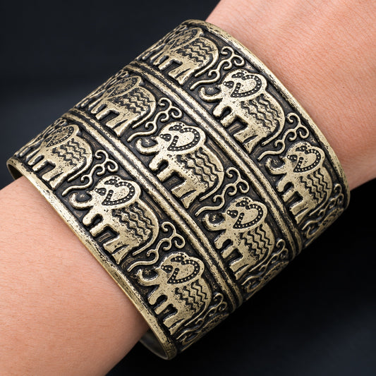 Woman wearing the Elephant Cuff Bracelet with engraved elephant pattern and antique gold finish.