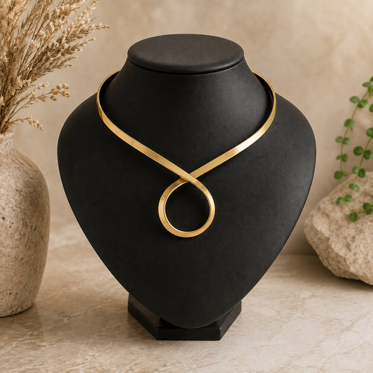 Enchantress Torque Collar Necklace in gold with sculptural open collar design and loop pendant detail.