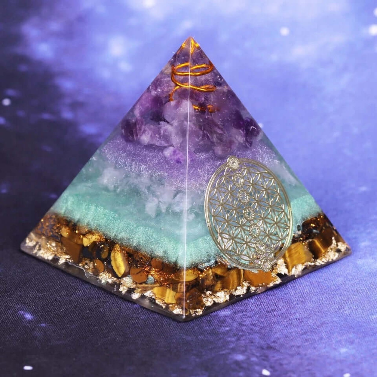 Angled view of the Flower of Life Crystal Pyramid with amethyst, tiger eye crystal base, copper spiral, and Flower of Life symbol.