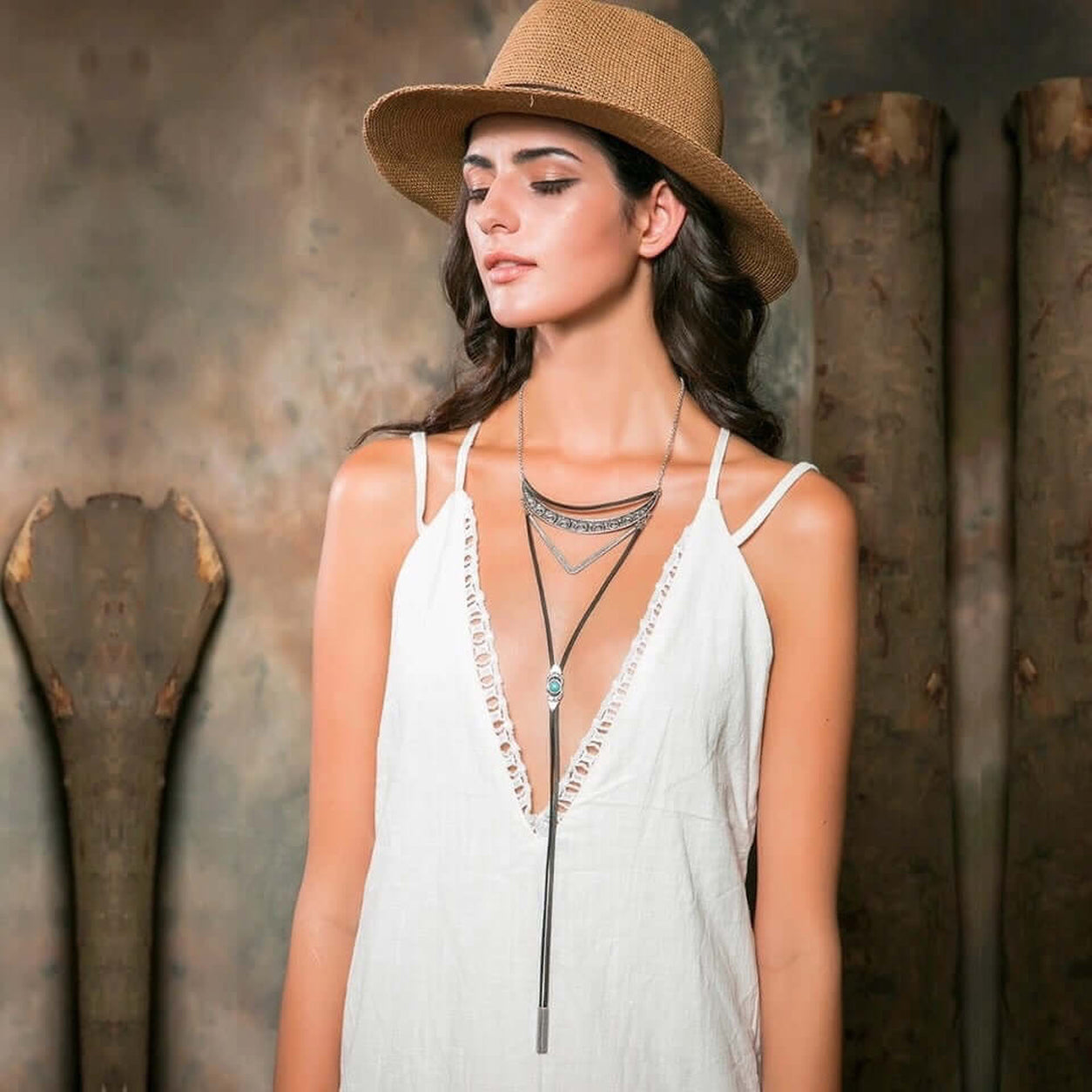 Geometric Bolo Necklace layered with antique bronze accents and adjustable black cord worn with a white boho dress.