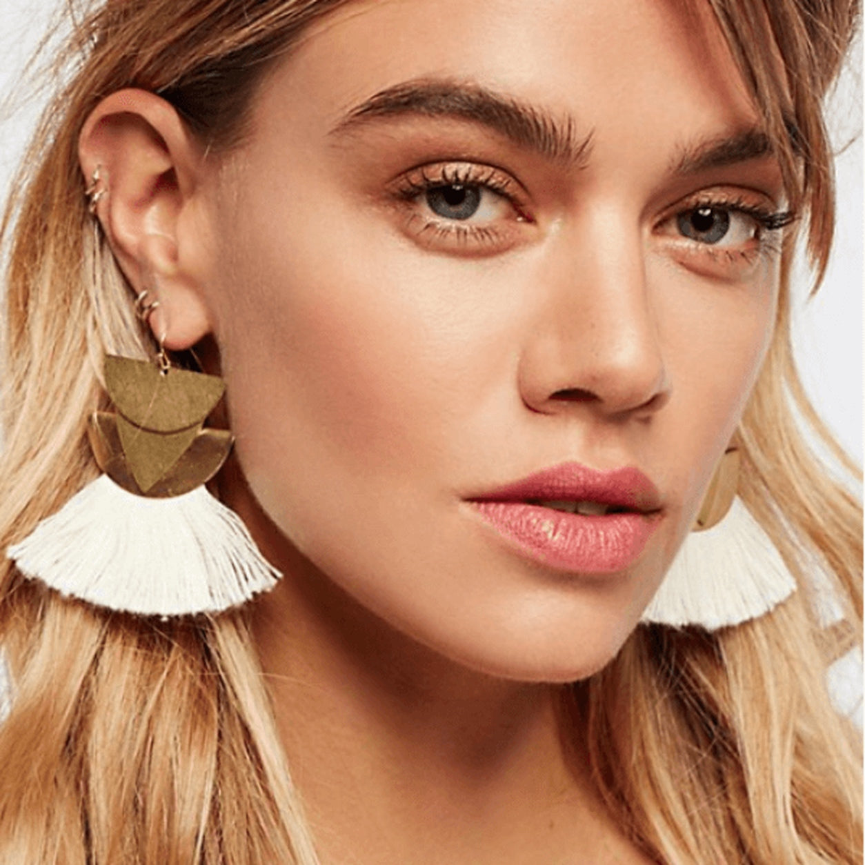 Woman wearing white Geometric Fan Tassel Earrings with layered gold geometric shapes and white fan tassels.