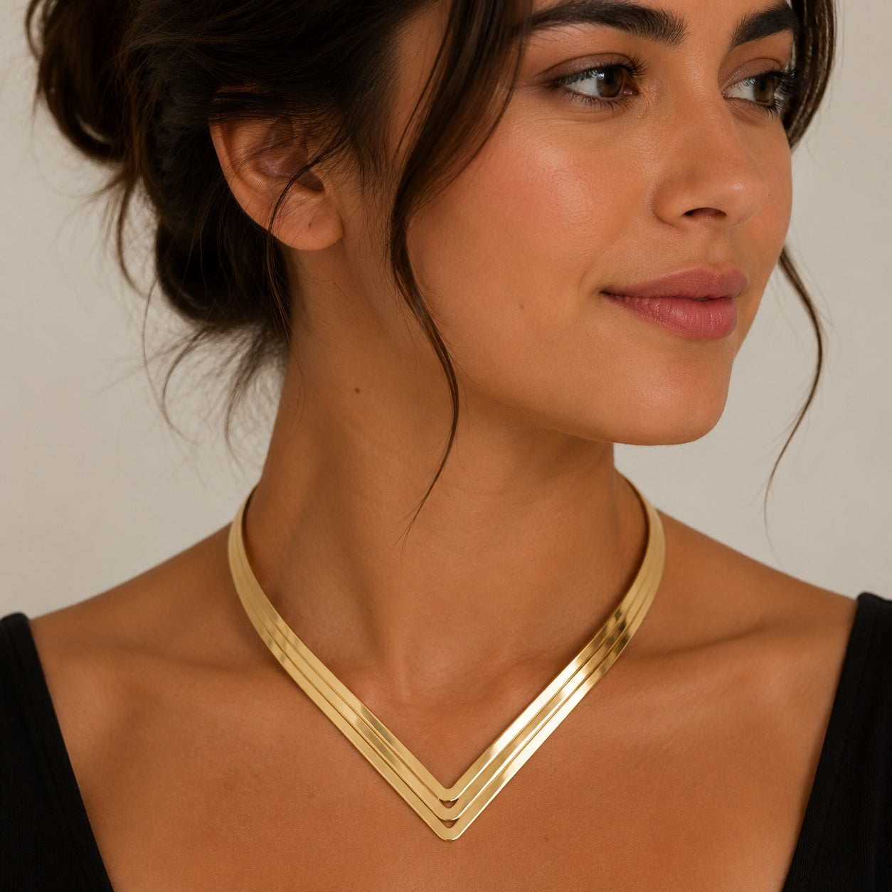 Woman wearing a gold Geometric Torque Collar Necklace with a polished V-shaped geometric collar design.