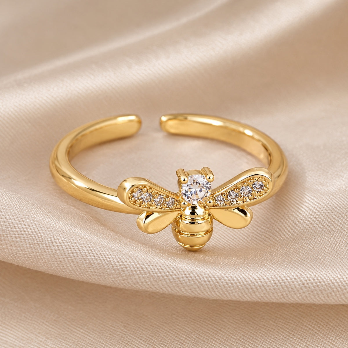 Front view of a gold bee ring with crystal-set wings and an open adjustable band