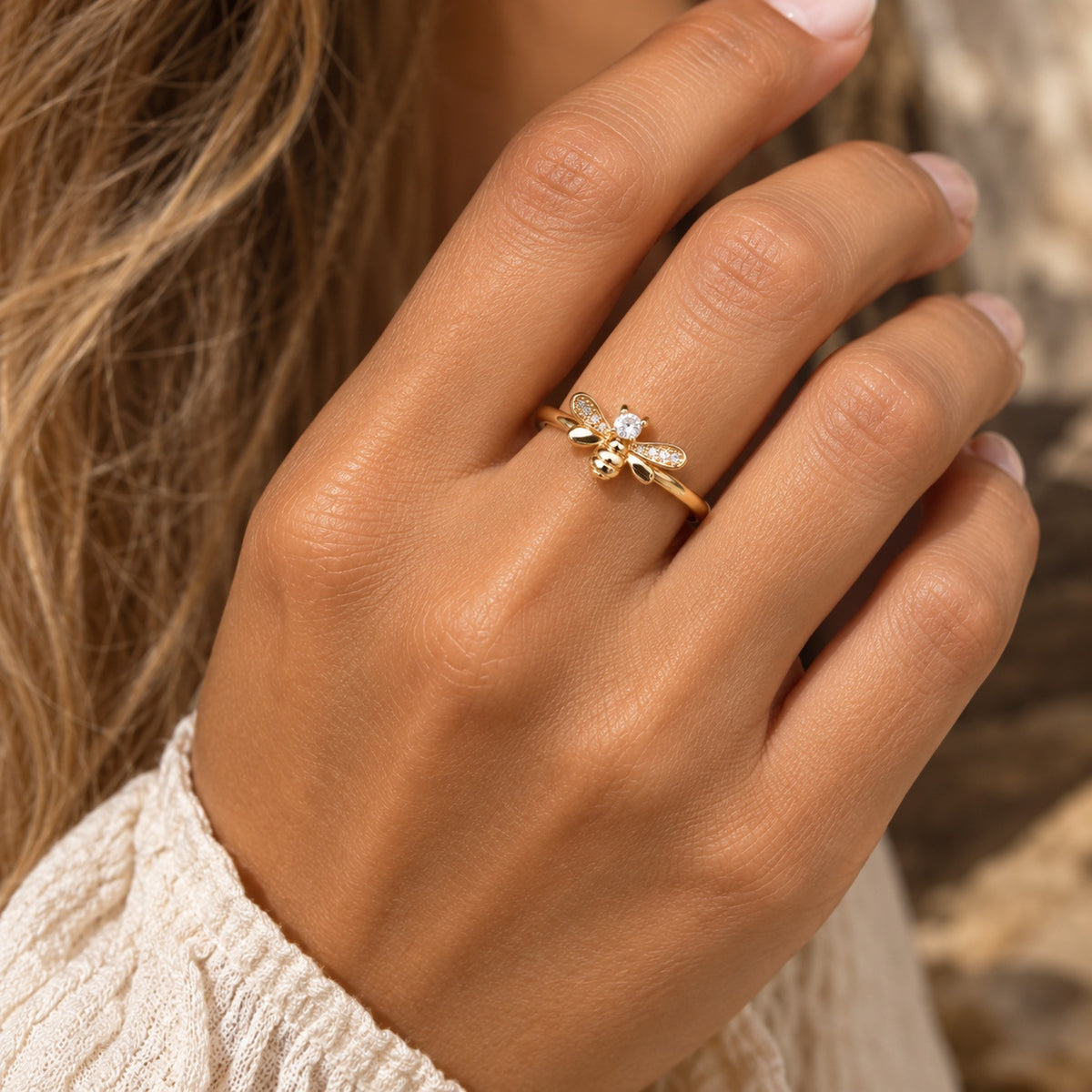 Gold bee ring with sparkling crystal wings worn on a woman's finger