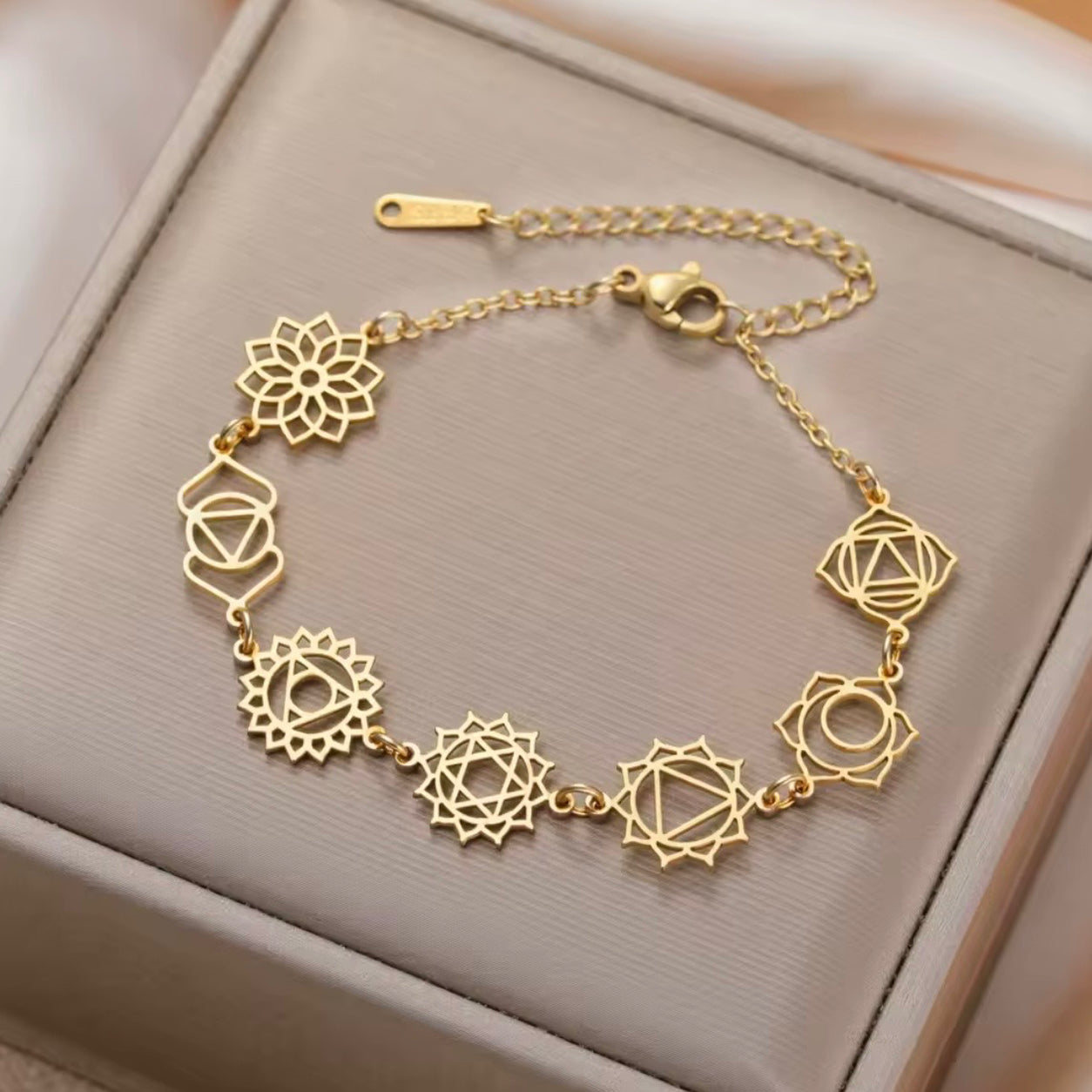 Gold Seven Chakras bracelet featuring seven chakra symbols on a soft jewelry box.