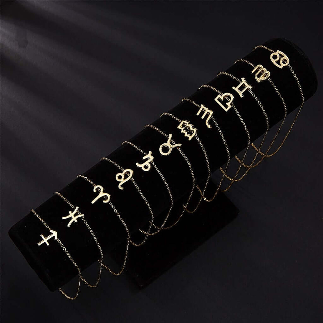 Gold Zodiac Necklace collection featuring all 12 zodiac sign pendants displayed together on black jewelry stand.