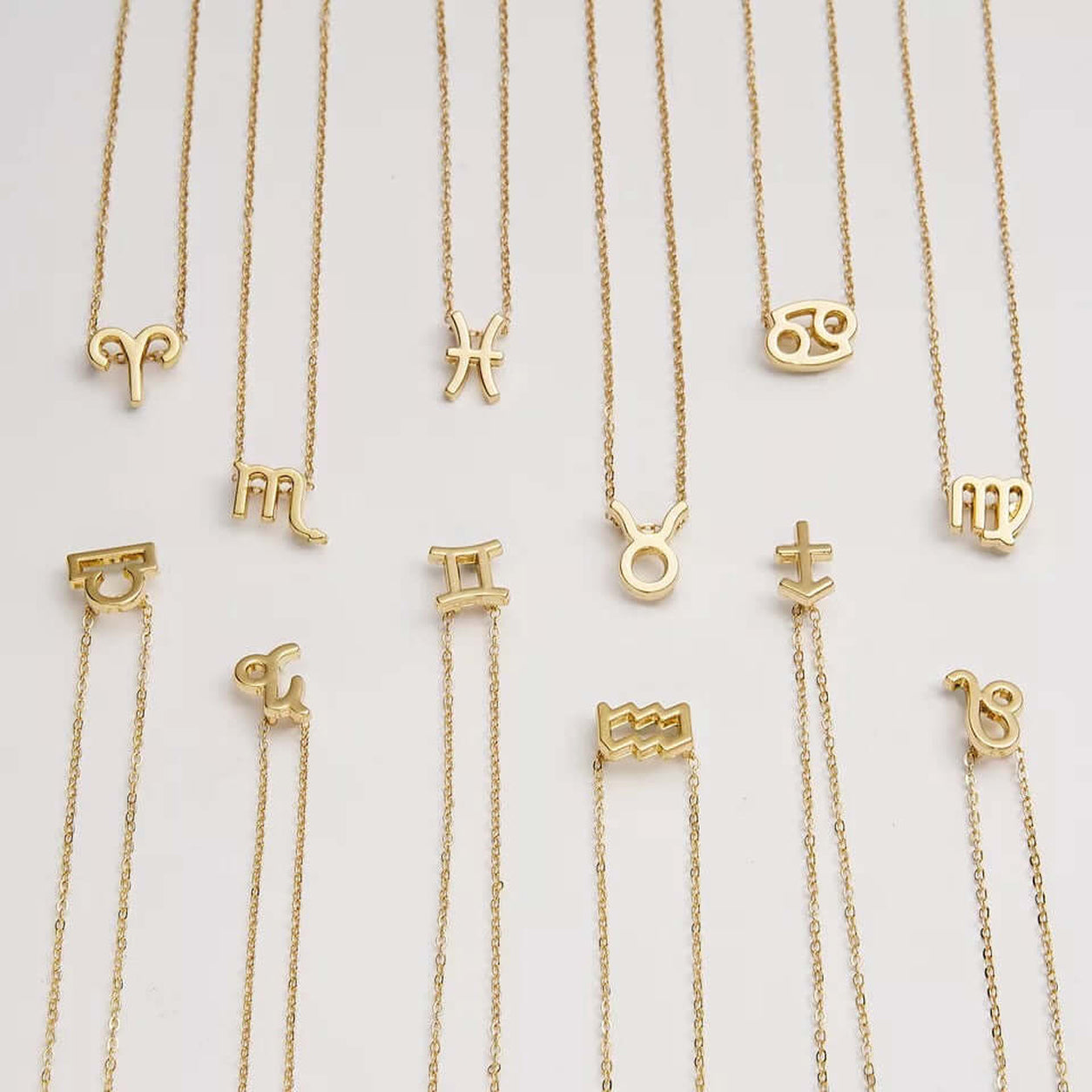 Gold Zodiac Necklace collection with all twelve horoscope sign pendants.