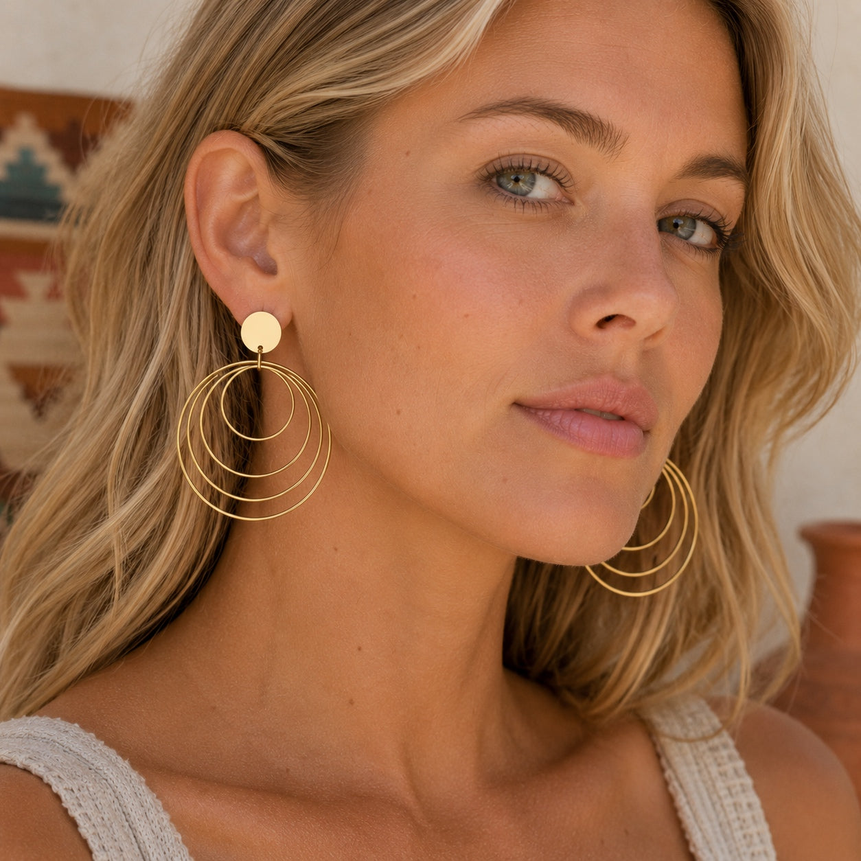 Woman wearing Golden Circles Dangle Earrings featuring layered gold circle hoops in a lightweight statement design.