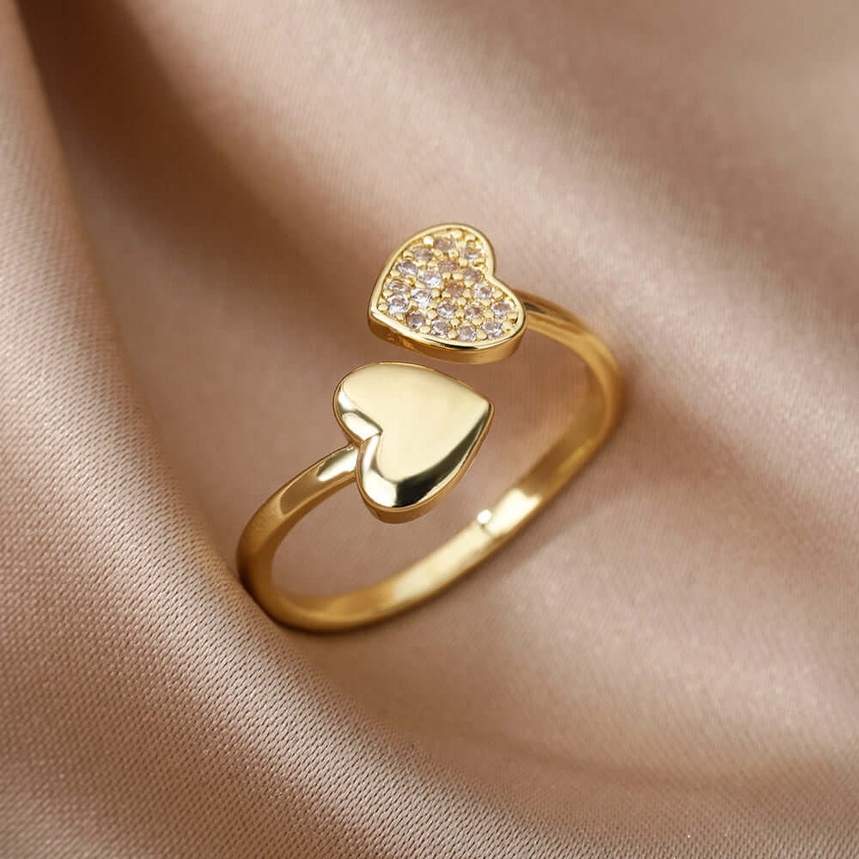 Hearts Of Gold Ring featuring an adjustable gold open-heart design with sparkling crystal on a champagne satin background.
