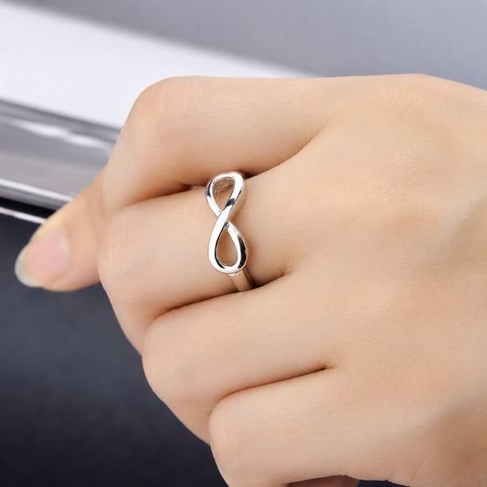 Infinity Ring in polished sterling silver worn on a woman’s hand, close-up lifestyle product photo.