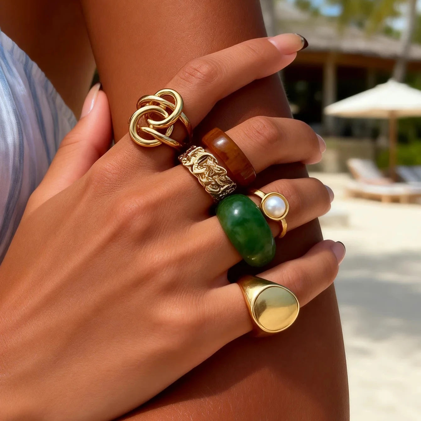 Woman wearing the Luxe Resin Statement Ring Set featuring gold-tone, resin, pearl, and green statement rings.