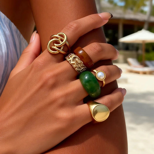 Woman wearing the Luxe Resin Statement Ring Set featuring gold-tone, resin, pearl, and green statement rings.