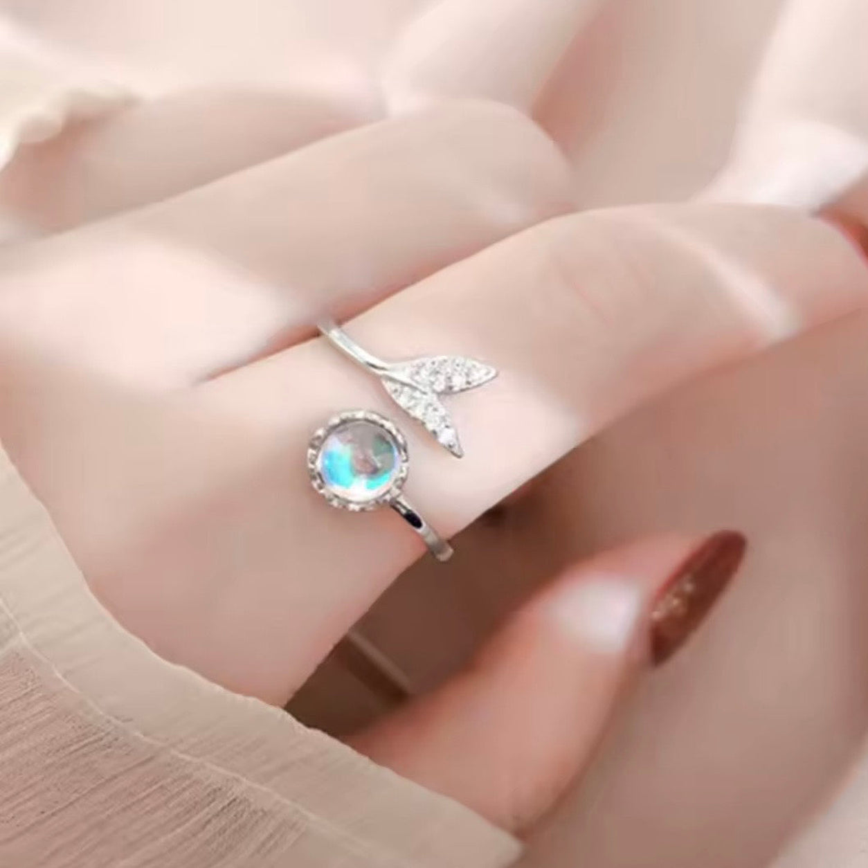 Close-up of the Mermaid Moonstone Ring worn on a finger, showcasing its shimmering moonstone and elegant open design.