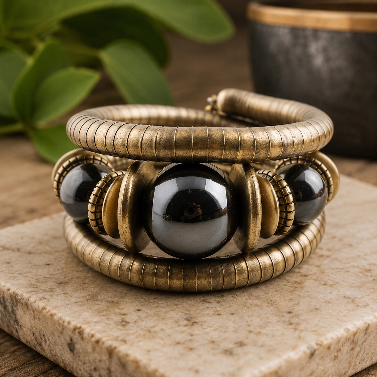Midnight Eclipse Coil Bracelet with antique bronze coil bands and glossy black bead accents on a natural stone display.