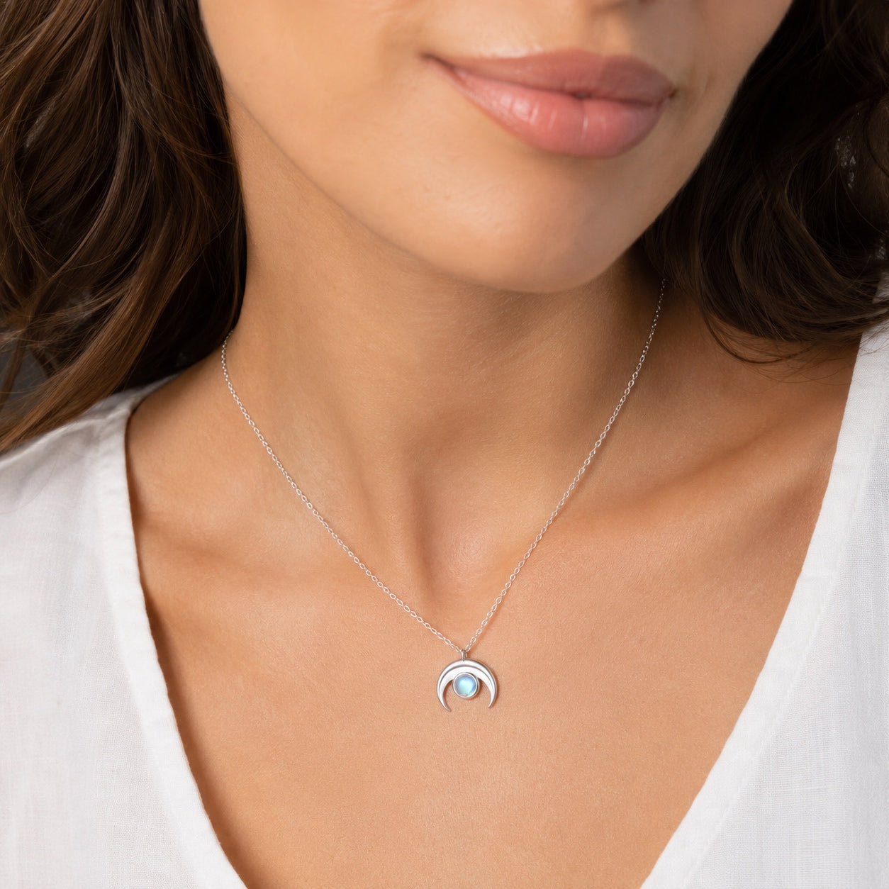 Woman wearing the Moonstone Crescent Pendant Necklace in sterling silver with a luminous moonstone pendant.