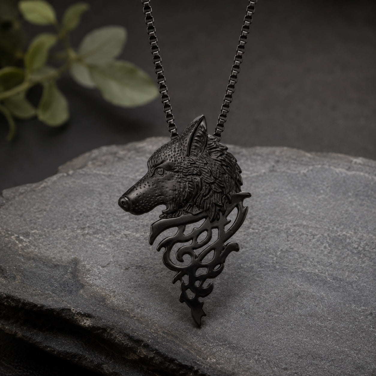 Black Mystic Wolf Pendant Necklace with engraved wolf head pendant displayed on stone with matching black box chain.
