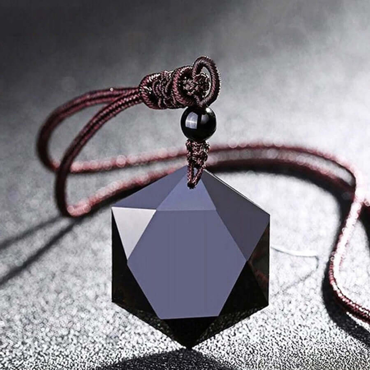 Obsidian Hexagon Pendant Necklace with faceted black gemstone on an adjustable brown cord in a close-up jewelry display.