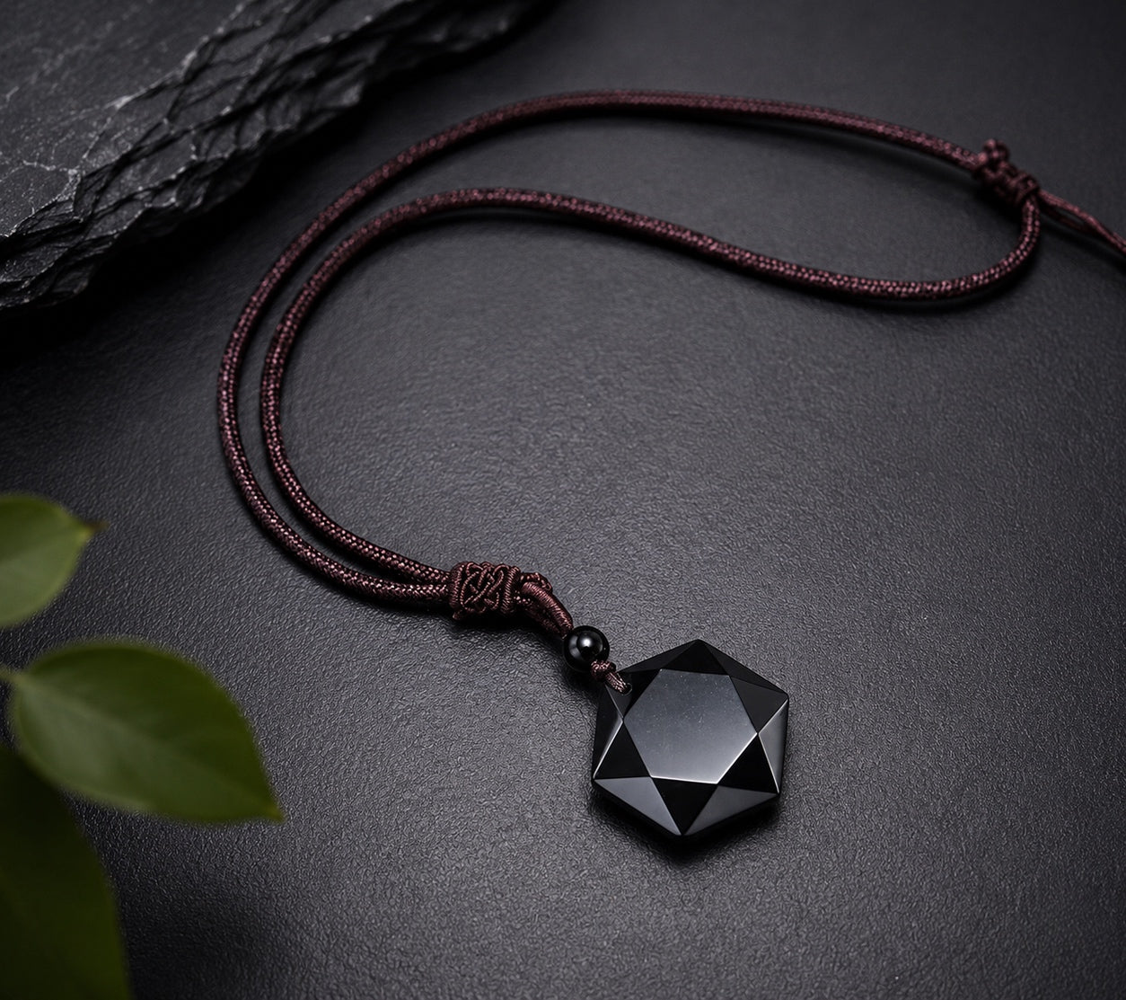 Obsidian Hexagon Pendant Necklace displayed on a dark textured surface with natural accents, highlighting its geometric black gemstone pendant.