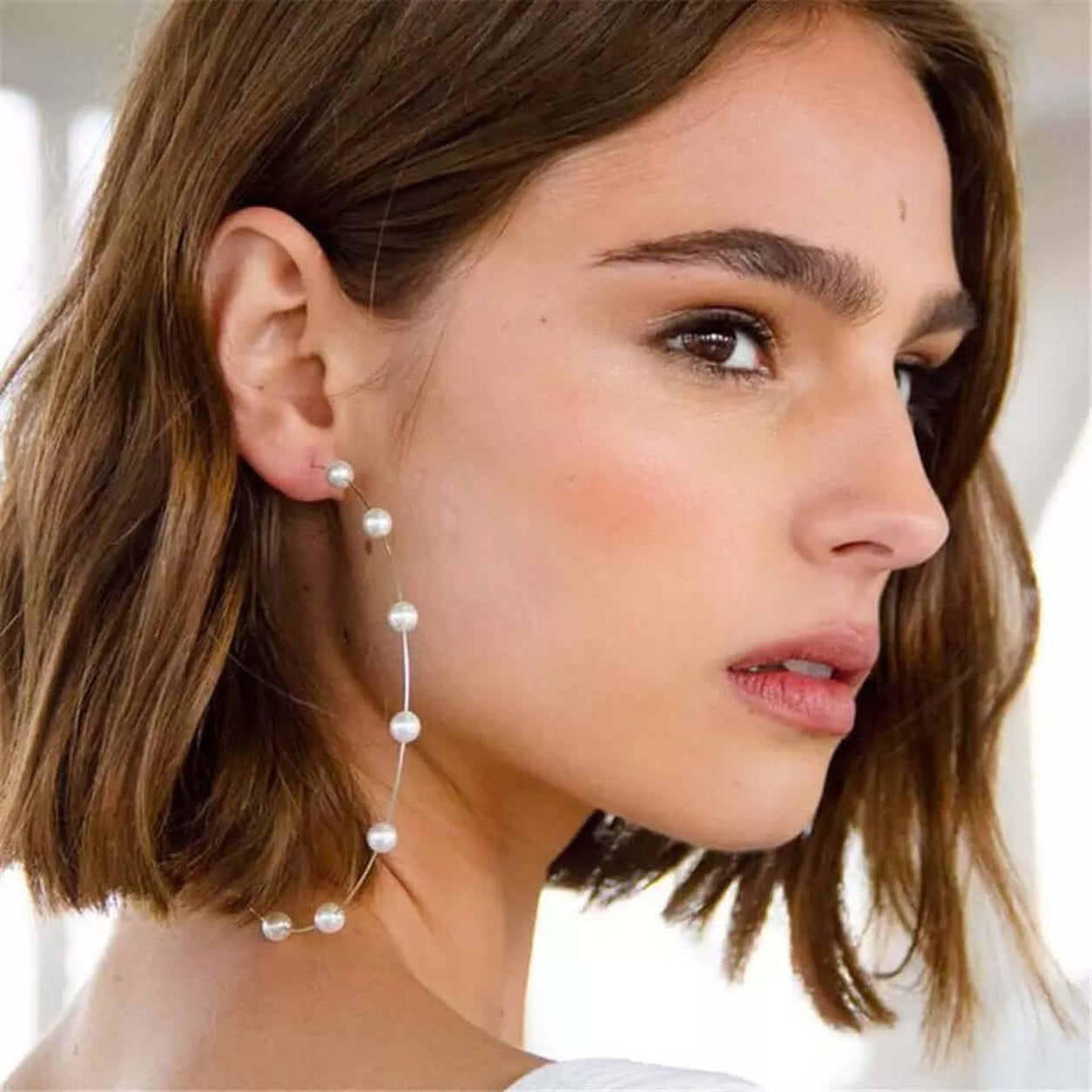 Side profile of model wearing oversized Pearl Hoop Earrings with floating pearl accents.