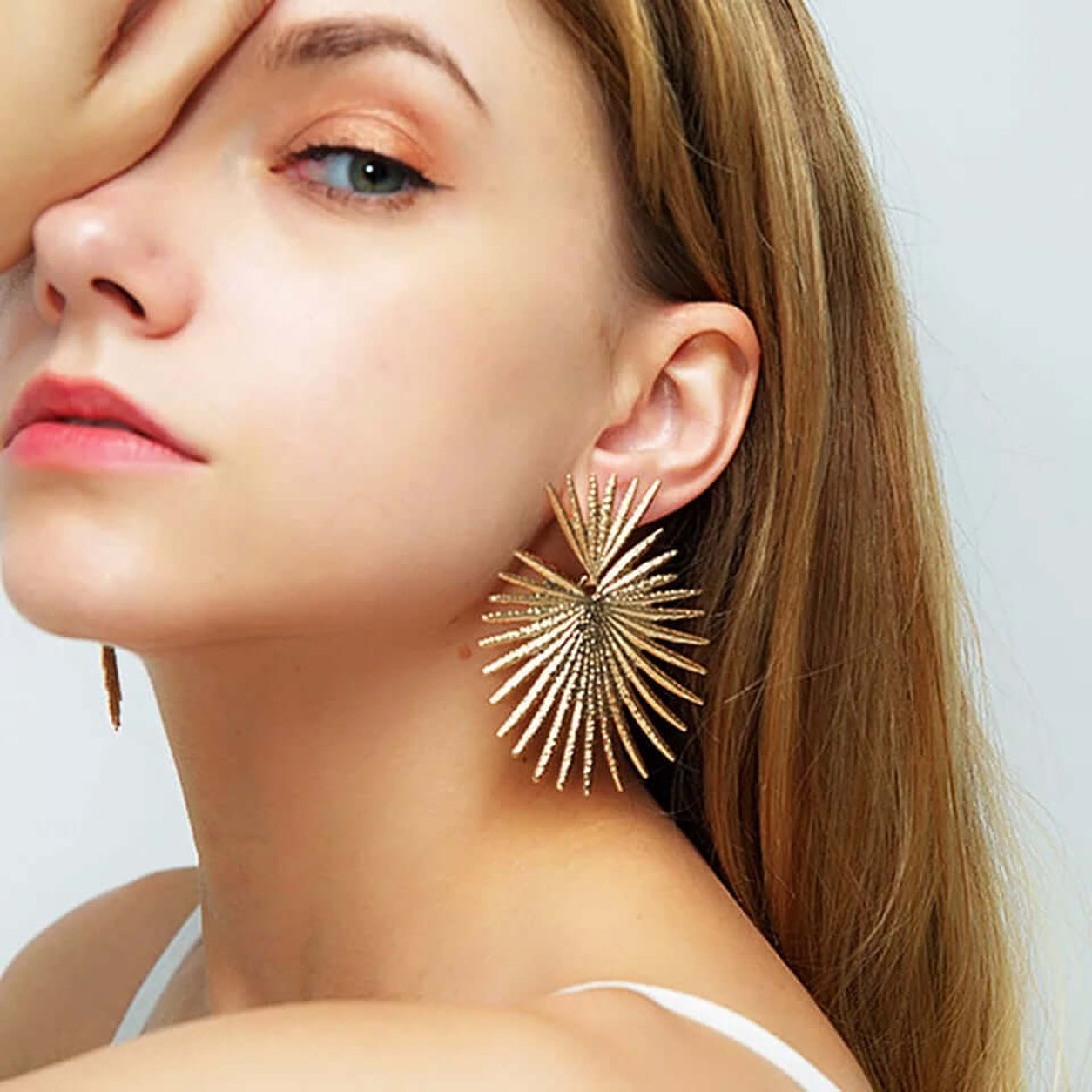 Model wearing gold Queen Of Hearts statement earrings showcasing the oversized sunburst fan design and elegant drop length.