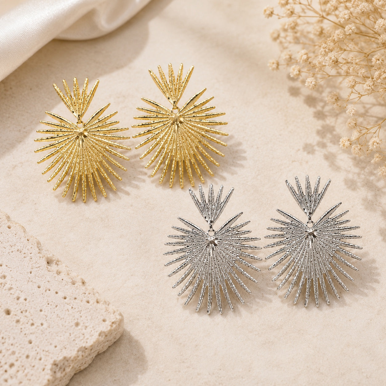 Queen Of Hearts statement earrings shown in gold and silver finishes featuring a bold sunburst fan design with lightweight drop styling.