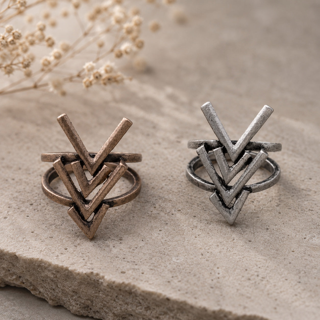Rustic Arrow Ring Set in antique bronze and silver finishes displayed on a natural stone surface.