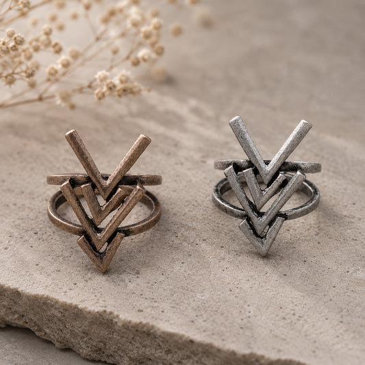 Rustic Arrow Ring Set in antique bronze and silver finishes displayed on a natural stone surface.