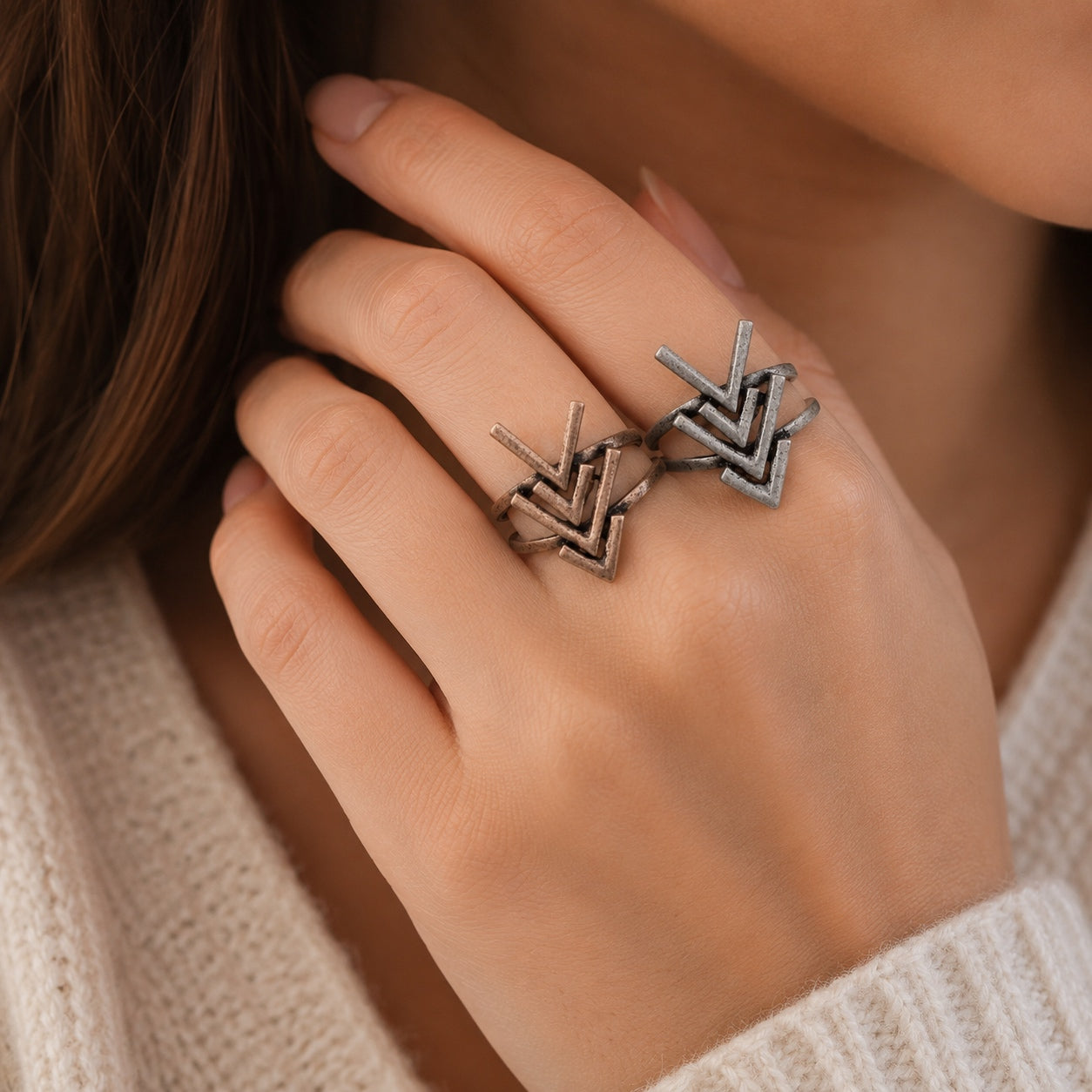 Woman wearing the Rustic Arrow Ring Set in antique bronze and silver with stacked geometric arrow designs.