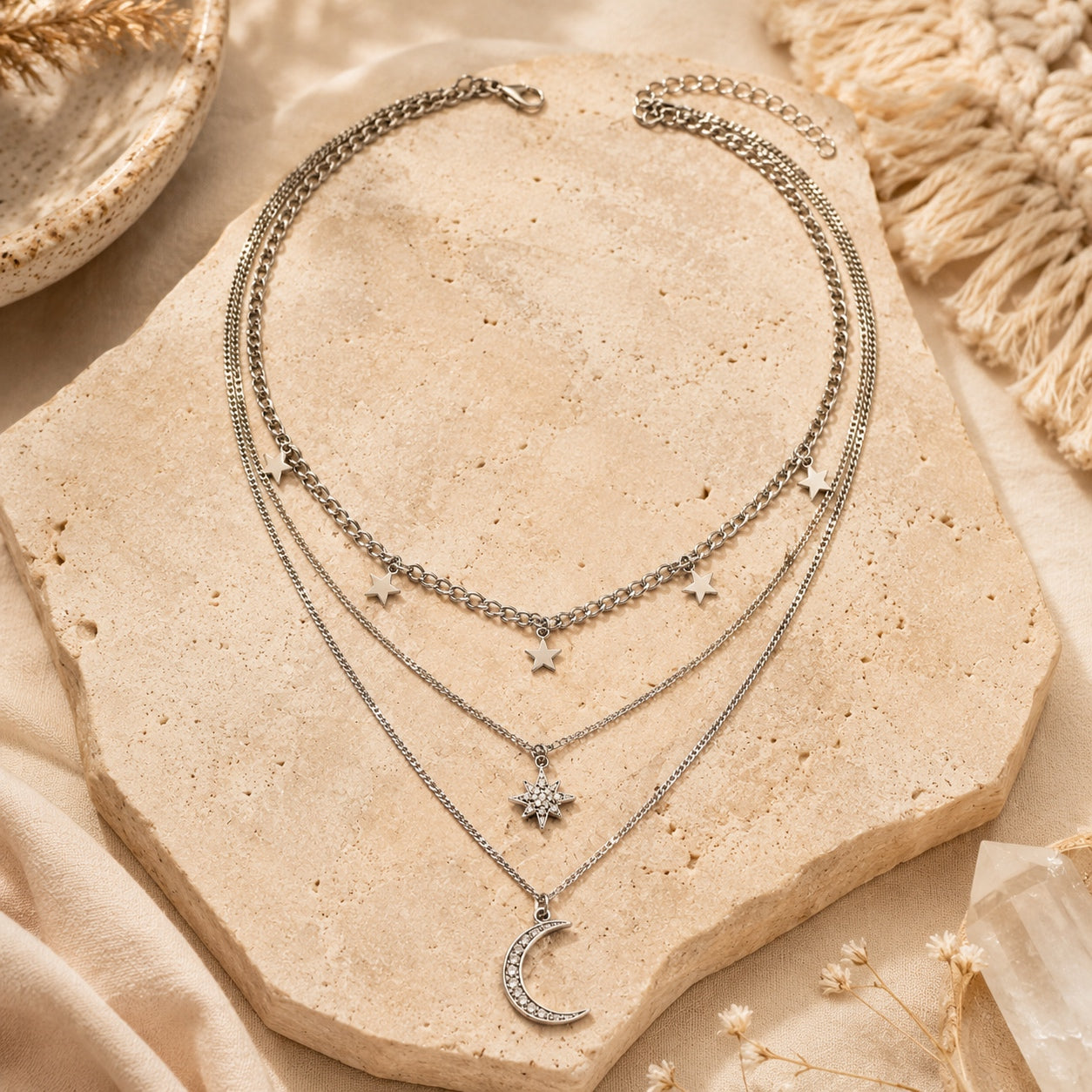 Silver layered necklace featuring dangling stars, a starburst pendant and crescent moon charm.